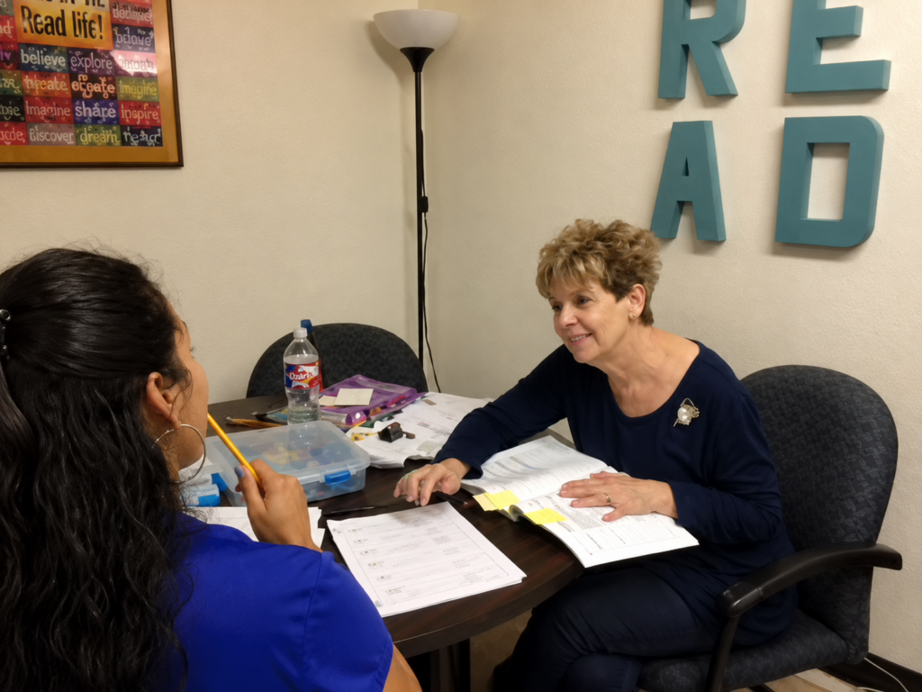 A Literacy ConneXus literacy coach works one-on-one with an adult learner, using worksheets and learning materials to help her strengthen her reading and writing skills.